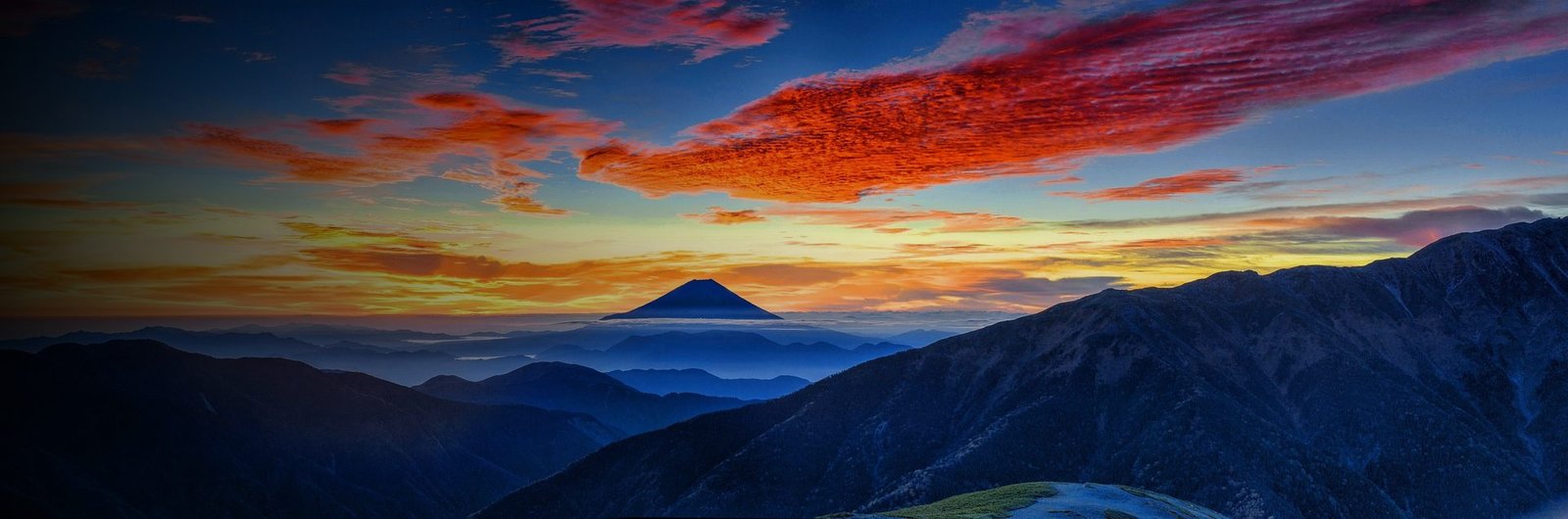 Mount Fuji at sunrise seen across mountain ridges